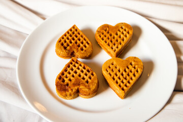 several waffles that looked delicious in the shape of a heart were served on a white plate