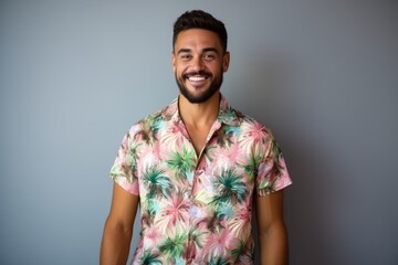 Handsome young man in a floral shirt smiling against a grey background