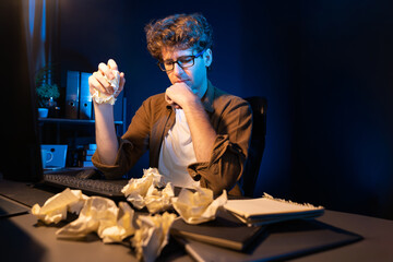 Stressful creative manager working with overworked project surrounded crumpled papers while waiting...
