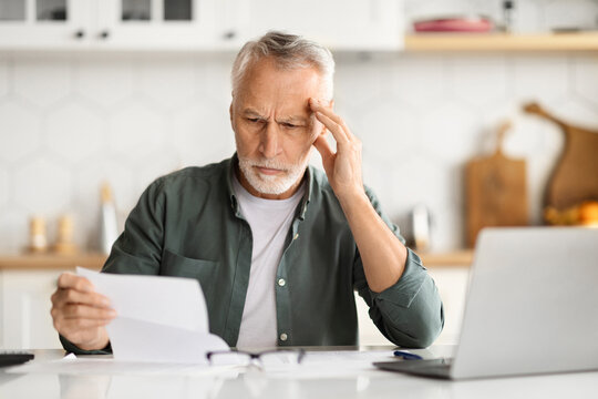 Distressed Elderly Man Touching Head, Feeling Overwhelmed When Doing Paperwork At Home