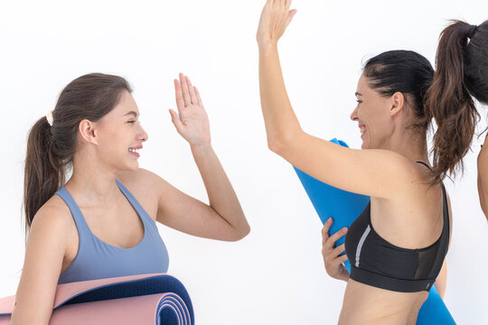 Group of happy sporty women talking with body stylish sportswear holding personal carpets leaned on a white background. waiting for yoga class or body weight class. healthy lifestyle and wellness