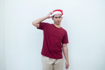 Young Asian man wearing a Santa Claus hat expressing confusion, thinking, and then having an idea, isolated by a white background for visual communication