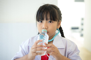 Asian girl in doctor's uniform drinking water from a bottle