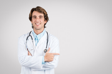 Smiling doctor pointing to the side, stethoscope visible