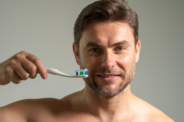 Man applying toothpaste on brush in bathroom, closeup. Attractive man looking down on toothpaste...