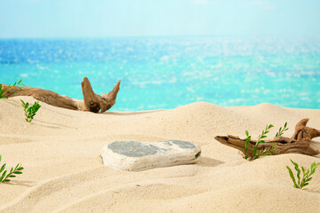Blue sea filled with sunshine, a block of stone on sand background with dry twigs and green grass....