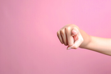 Woman hand pointing finger at camera isolated on the pink background