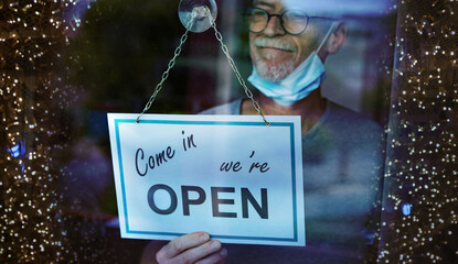 Store owner hanging open sign on window; light effect