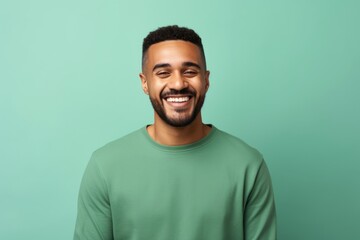 Happy african american man in green t-shirt on turquoise background