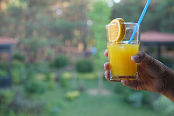 holding a glass of orange juice outdoor 