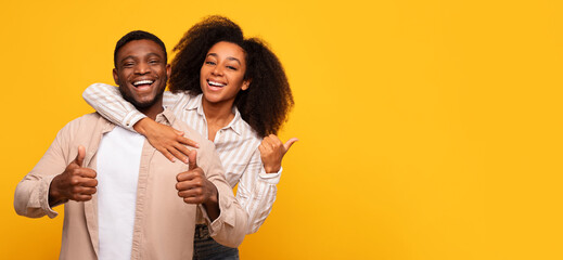 Happy couple giving thumbs up on yellow background - obrazy, fototapety, plakaty