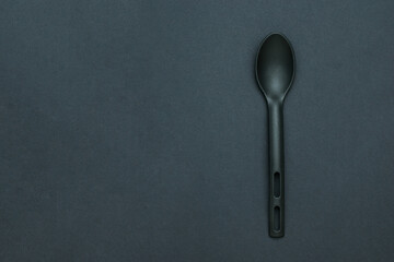A large black silicone spoon on a black background.