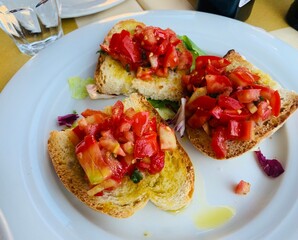 Vibrant Italian Bruschetta with bright red tomatoes and olive oil in Italy on a white plate