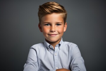 Portrait of a cute little boy in a blue shirt on a gray background - obrazy, fototapety, plakaty