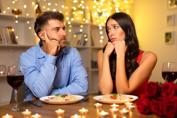 Thoughtful couple during dinner, pondering with chins rested on hands