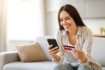 Young woman with credit card and smartphone in hand making online shopping