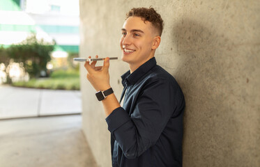 A happy young man in a navy shirt, using voice command on a smartphone