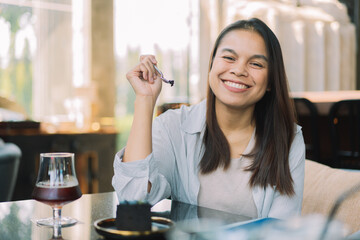 Young woman is happy and enjoys eating sweets and coffee at a cafe.