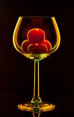 Wine glass with cherry tomatoes inside isolated on black background.  - 707525479
