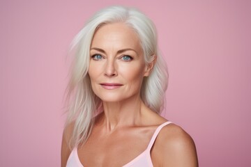 Portrait of beautiful mature woman with blonde hair on pink background.