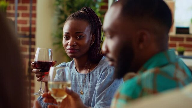 African american woman at apartment party watching man share interesting story, having crush on him. Guest at home gathering in love with charming BIPOC host captivating friends with tale