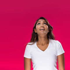 Indian Woman looking upwards on pink background.