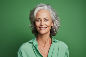 Smiling senior woman with grey hair. Portrait of beautiful mature woman with grey hair on green background.