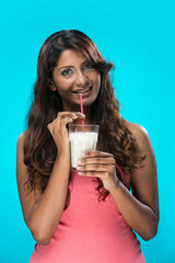 Indian Woman drinking glass of milk on blue background.