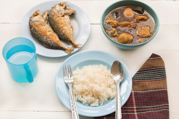 rice, fried mackerel fish, curry and water healthy thai foods arrangement flat lay style on background wooden