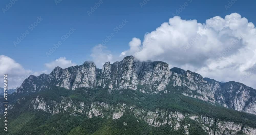 Sticker aerial time lapse video of the white clouds rise from the cliffs with swirling around mountain peaks