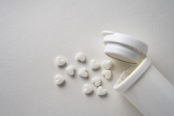 Heart shaped pills on a white background with copy space