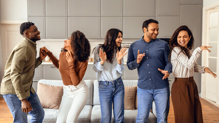 Fototapeta premium Multiracial group of friends dancing enjoying students party at apartment
