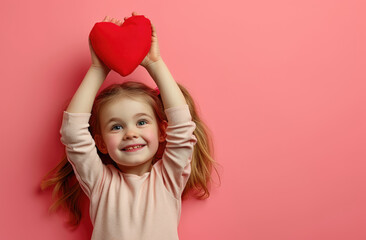 a beautiful little girl holds up a red heart on pink background