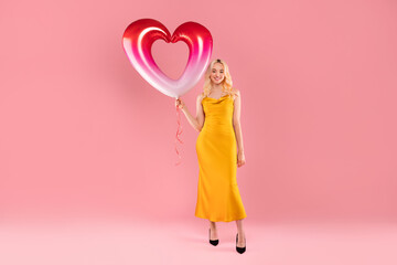 Elegant woman with a pink and white heart balloon on pink backdrop