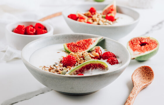 Granola with yogurt, figs and raspberries in bowls