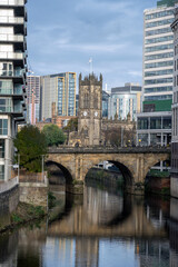 View along the river Irwell to the cathedral in Manchester, UK