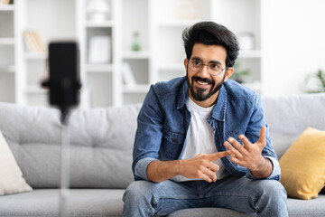 Friendly indian man recording vlog on his smartphone at home