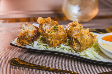 Fried crab meat or hoi jo. On a plate with dipping sauce.