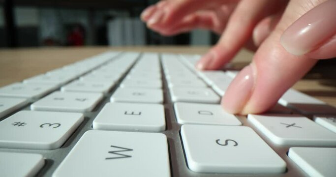 Female worker prints message on modern computer keyboard
