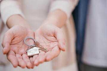 Landlord's hand presents keys for a new house. Symbolizes investment tenant security and real...