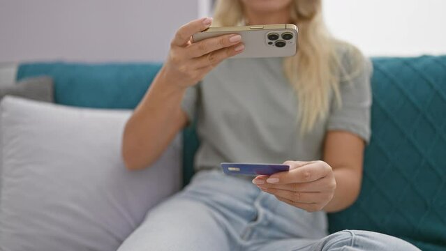 Blonde woman takes a photo of her credit card indoors on her smartphone