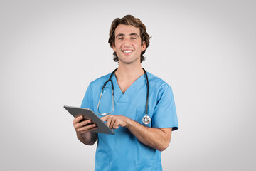 Smiling male nurse in blue with tablet for health records