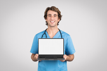 Happy male nurse presenting laptop with white blank screen