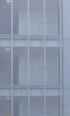 White perforated mesh screens on the exterior of an apartment building. Visible over three levels
