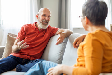 Happy Senior Man Relaxing On Couch And Chatting With Wife At Home