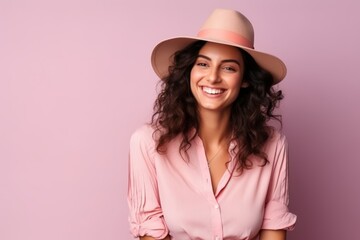 Portrait of a beautiful young woman in hat smiling over pink background