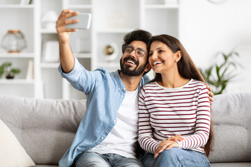 Loving beautiful indian couple taking selfie together at home