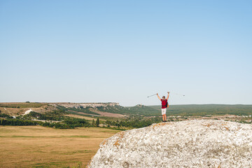 Full body of male traveler standing on rocky mountain on summer day