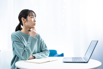 パソコン作業をし考える若い日本人女性