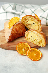 Glazed croissant with dried orange on wooden board